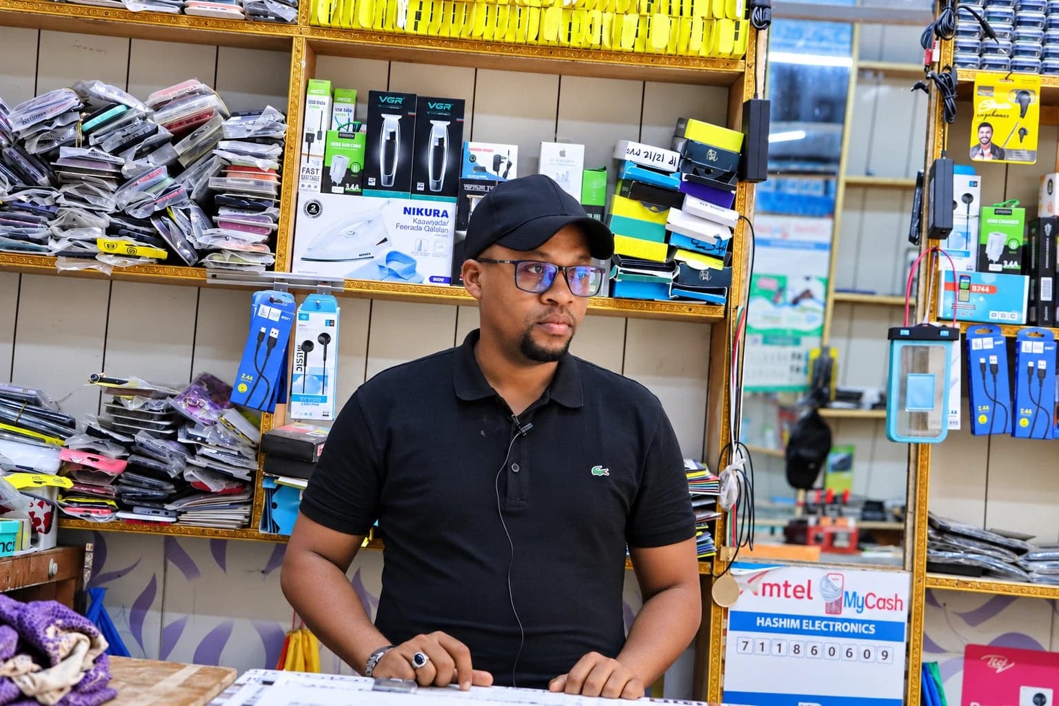 A trader at the counter of his mobile phone and electronics shop